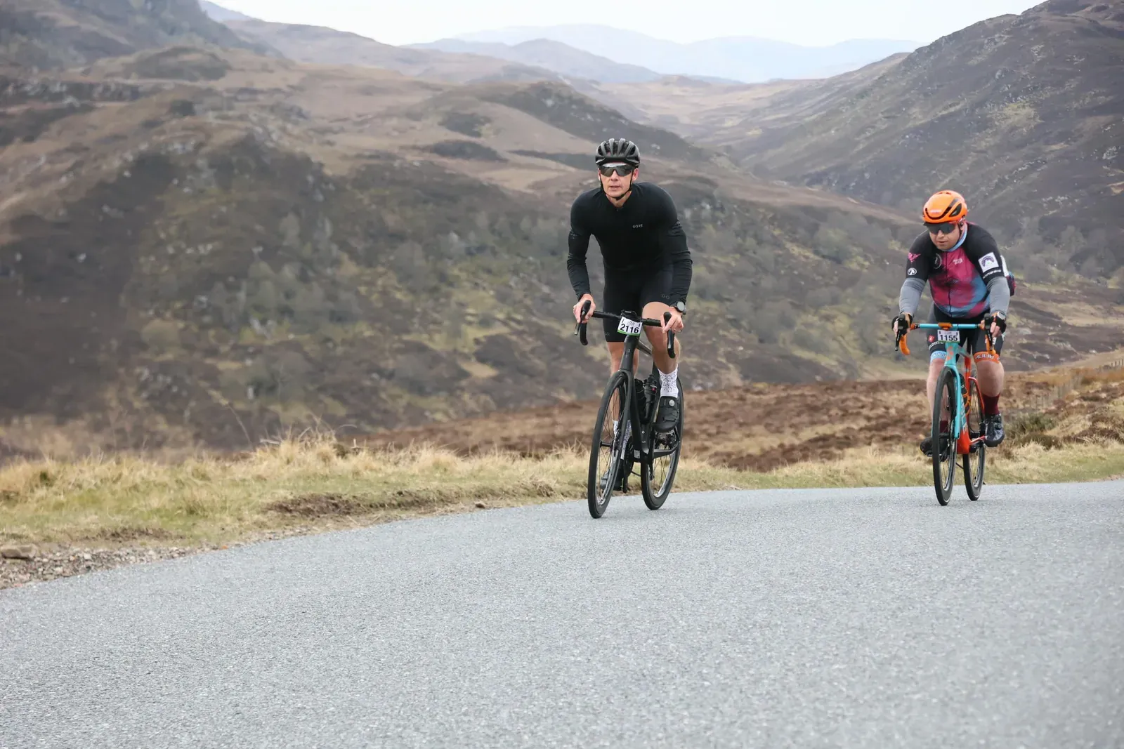 Two cyclists climbing a moorland road