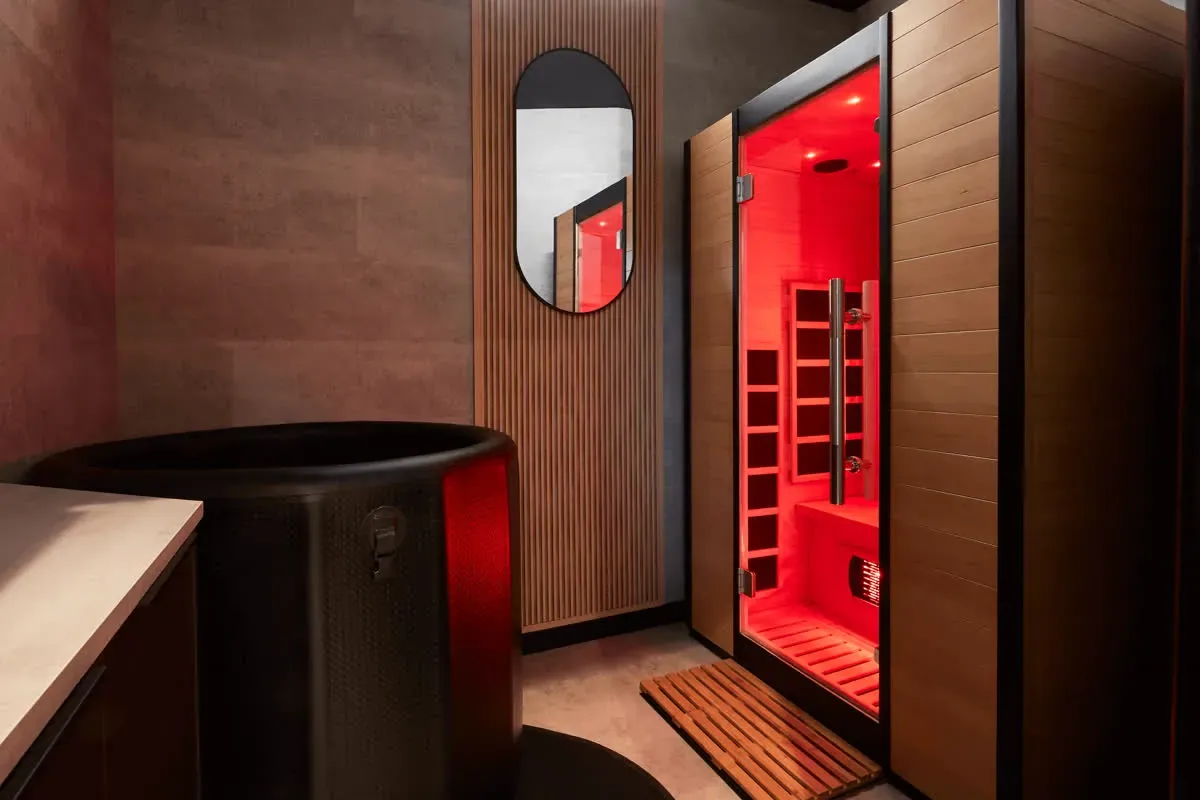 The ice bath in front of the lit infrared sauna